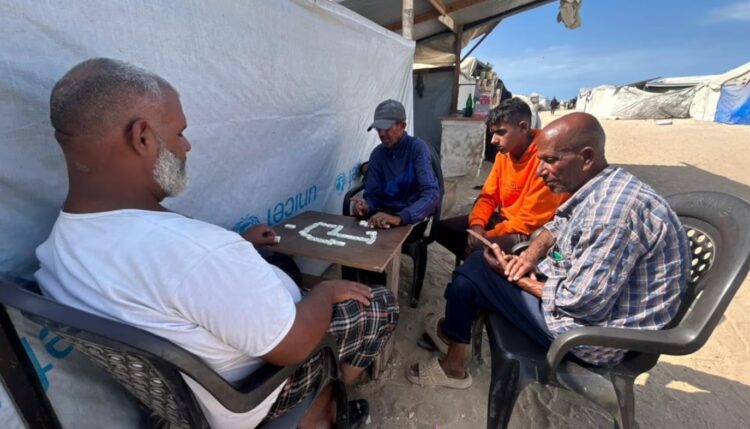 Mohammed Hamdan Abu Shahab, de 40 años, juega a un juego de mesa con su hijo Naim y sus amigos en la playa de Gaza, el 9 de octubre. Es la primera vez en cinco meses que se siente lo suficientemente seguro como para disfrutar de este sencillo placer.Mohamed Solaimane